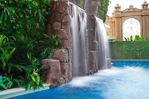 Artificial waterfall with a pool surrounded by plants. 写真素材