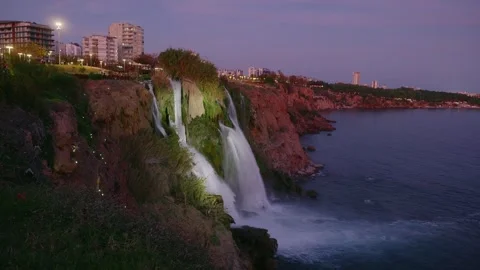 Artificially lit waterfall cascading beneath violet evening sky Video stock 331556928