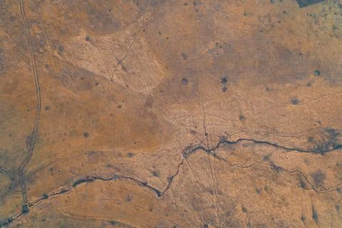 Artillery craters in dry grass field near small winding stream showing scarred Stock Photos