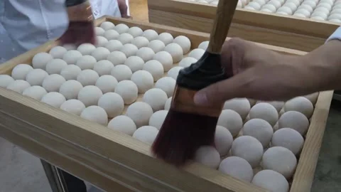 Artisan Baker Brushing Egg Wash on Round Dough Balls in Wooden Tray Stock Footage 345291956