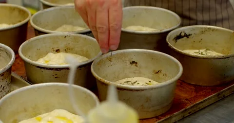 Artisan baker placing fresh dough into round metal molds on bakery tray closeup Stock Footage 344597101