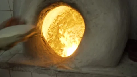 An artisan baker puts chapatis cakes in a traditional oven, in Bahrain Stock Footage 245248301