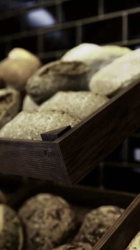 Artisan bread displayed on wooden racks in a cozy bakery environment Stock Footage 314257451