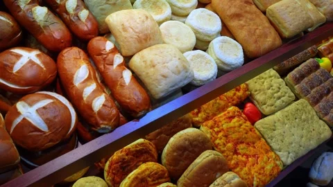 Artisan breads and savory pastries displayed on bakery shelves. A high angle Stock Footage 336339392