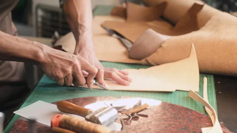 Artisan carefully using a sharp knife to shape the leather on cutting mat in his Video stock 281408391
