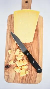 Artisan cheese block with knife on rustic wooden board isolated on white ba.. Stock Photos