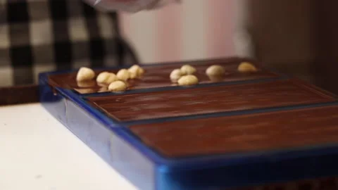 Artisan choclatier adding nuts in liquid choclate molds Stock Footage 147987812