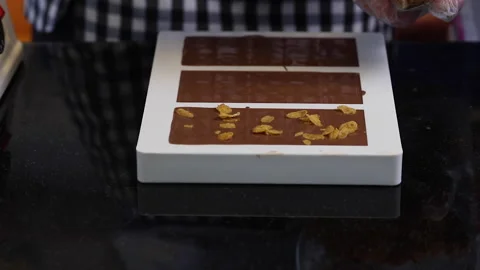 Artisan choclatier inserting chips in liquid choclate molds Stock Footage 147987919