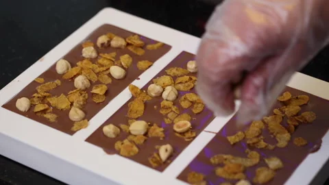 Artisan choclatier inserting nuts in liquid choclate molds Stock Footage 147987468