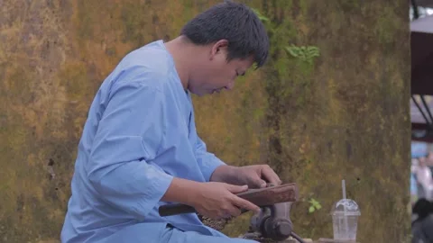Artisan craftsman skillfully shaping wood in a vibrant market setting Stock Footage 312242537
