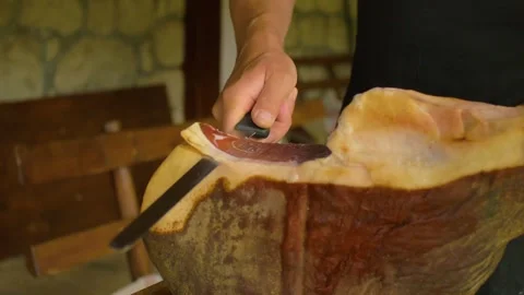 An artisan cuts a slice of ham to serve it in an authentic restaurant, in Bosnia Stock Footage 241611543