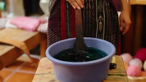 Artisan dips yarn into natural dye for handmade textile weaving Stock Footage 328913266