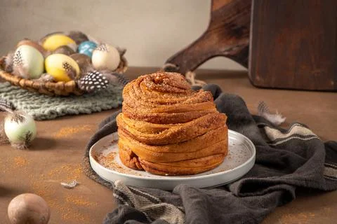Artisan Easter Cinnamon Roll with Pastel Eggs and Feathers Foto stock