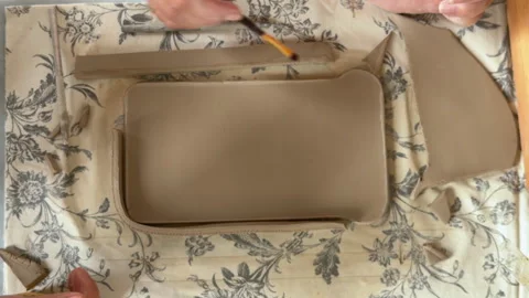 Artisan hand building slab clay pottery on floral cloth workbench Stock Footage 343900365