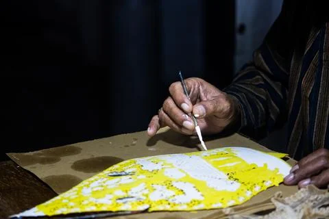 Artisan hands applying fine white paint on Javanese leather puppet in tradi.. Stock Photos