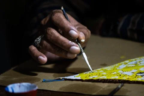 Artisan hands applying fine white paint on Javanese leather puppet in tradi.. Stock Photos