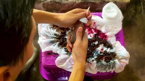 Artisan Hands Applying Liquid Dye Directly on Tied Fabric Stock-Footage 336796746