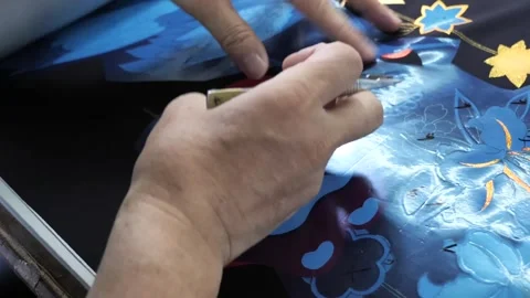 Artisan hands perform intricate fine brushwork detailing on a blue floral Stock Footage 339123502