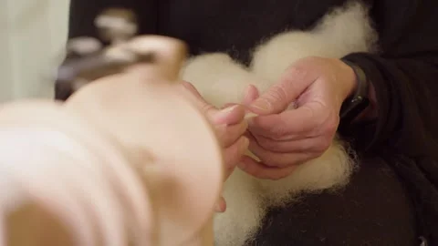 Artisan hands pull wool being twisted by modern spinning wheel bobbin Stock Footage 274780255