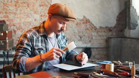 Artisan in his workshop makes a leather wallet. The concept of handicraft Stock Photos