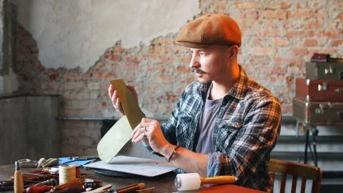 Artisan in his workshop makes a leather wallet. The concept of handicraft Stock Photos