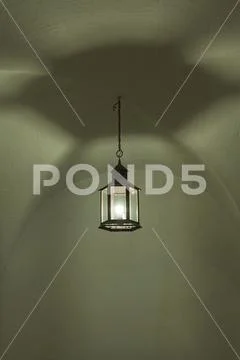 An artisan lamp hangs from an old vault in a medieval building. Stock Photos