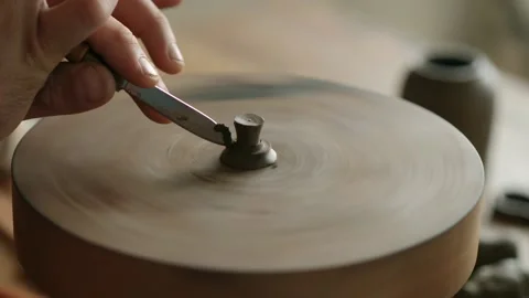 Artisan makes the shape with a knife the handle of the lid of a clay teapot Stock Footage 145534551