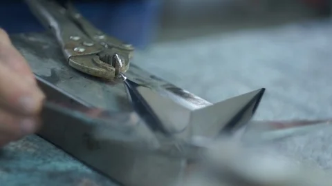 Artisan man working metal using pliers on his workbench close up Stock Footage 117360547