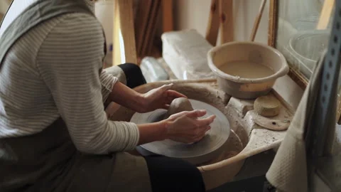 Artisan potter pressing and tapping clay onto the wheel, preparing to shape.. Stock Footage 274164100