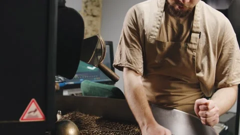 Artisan roaster skillfully prepares fresh coffee beans in a cozy roasting space Video stock 321765753