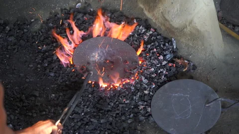 Artisan rotating and heating raw bell metal in charcoal forge furnace Video stock 342314464