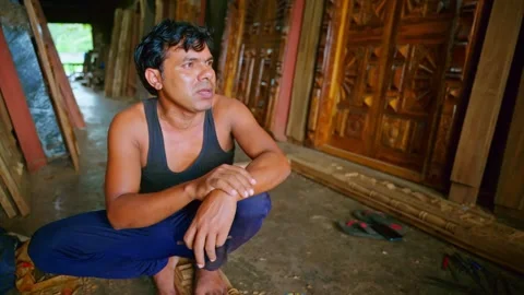 Artisan seated on floor gestures as explaining work Stock Footage 313666773