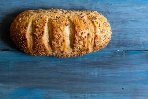 Artisan seed bread on a blue table, ideal for tapas or sandwiches Stock Photos