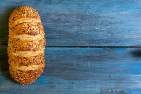 Artisan seed bread on a blue table, ideal for tapas or sandwiches Stock Photos