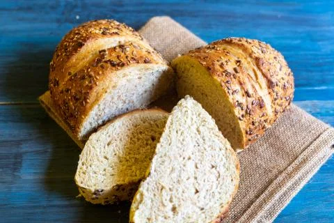 Artisan seed bread on a blue table, ideal for tapas or sandwiches Stock Photos