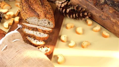 Artisan seeded bread loaf sliced on wooden board, paired with pinecones and Stock Photos