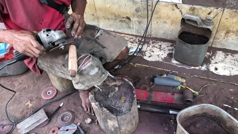 Artisan sharpens a blade with a handheld grinder, Stock Footage 321235214