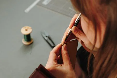 Artisan trims thread after hand stitching a leather wallet. Detailed finish.. Stock Photos