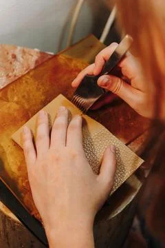 Artisan uses a pricking iron to create stitching holes in textured leather. Stock Photos