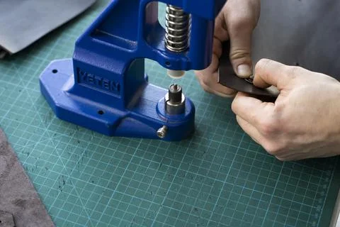Artisan using hand press for setting snaps in leather for makes a wallet. Hand Stock Photos