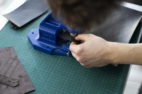 Artisan using hand press for setting snaps in leather for makes a wallet. Hand Stock Photos