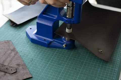 Artisan using hand press for setting snaps in leather for makes a wallet. Hand Stock Photos
