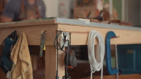 Artisan works in the background at his workbench as measuring tape, Stock Footage 124990620