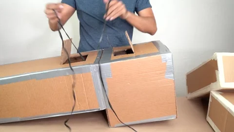 Artist adding plastic raffia to carbdoard box crafts making piñata Video stock 328160545