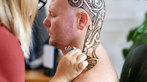 Artist applying henna tattoo on white skin, Caucasian man head, also on the neck Stock Footage