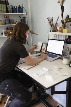 Artist checking her receipts using laptop Fotos de archivo