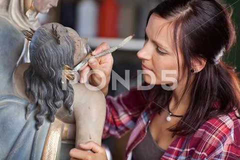 Artist cleaning statue with spatula Stock Photos