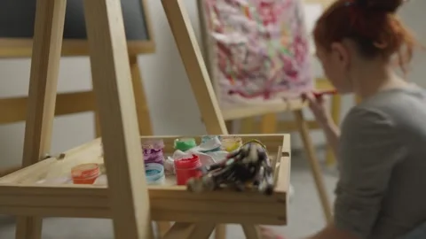 The artist creates a drawing on an easel using bright paints and brushes in the Stock Footage 240848253