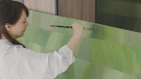 Artist creates vibrant painting using green hues in modern studio setting 스톡 동영상 322060384