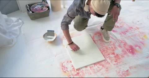 Artist is crouching on floor, scribing lines on canvas then is scraping to build Video stock 341665107